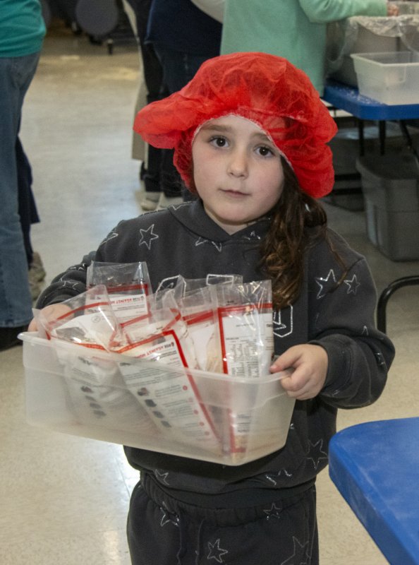 Fern Kluchnik is serious about her job carrying filled packets to the closing station.